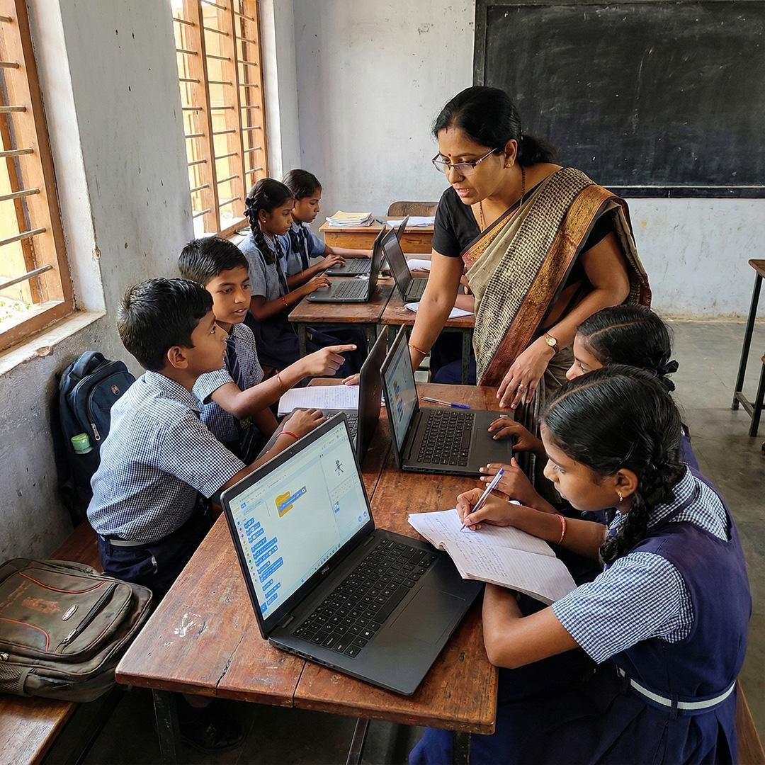 Students learning with laptops alongside their teacher